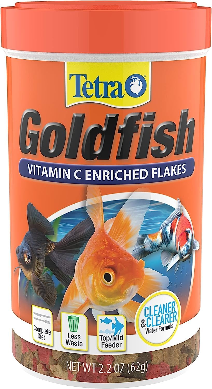 A hand sprinkling fish food flakes into an aquarium with colorful fish.